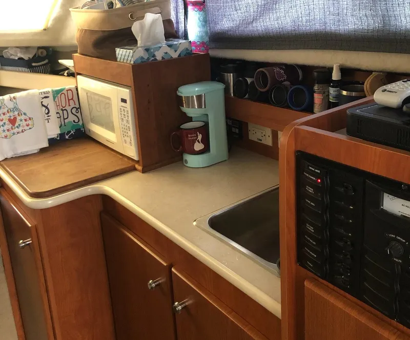 Slide: The Image of 2005 Bayliner 289 Classic boat kitchen with microwave, coffee maker, and wooden cabinetry. - 4