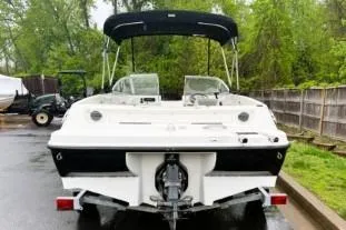 Slide: The Image of 2012 Bayliner 175 Bowrider boat with canopy, parked on a trailer in a wooded area. - 4