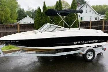 Slide: The Image of 2012 Bayliner 175 Bowrider on trailer, parked outdoors with trees and houses in background. - 5