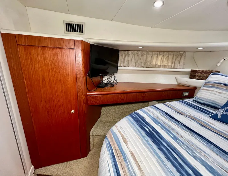 Slide: The Image of 2001 Maxum 4600 SCB yacht cabin with wood cabinetry, TV, and striped bedding. - 26