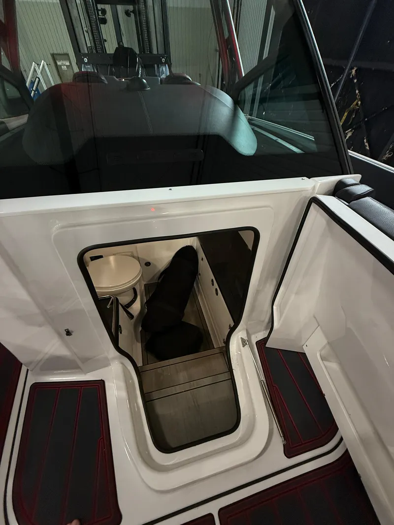 Slide: The Image of Interior cabin view of 2025 Monterey Elite 27 OB boat, featuring compact seating and toilet. - 12
