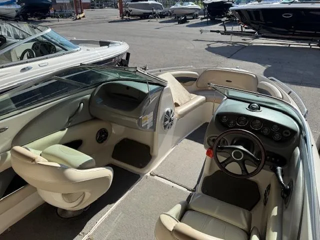 Slide: The Image of 2004 Chaparral 210 SSi boat interior with steering wheel and seating, docked outdoors. - 14