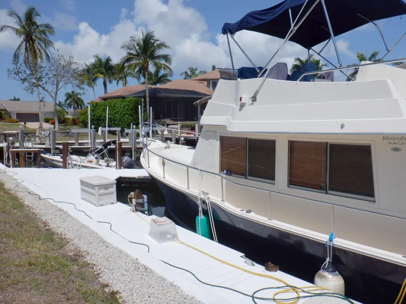 Slide: The Image of 2006 Mainship 34 Trawler docked, surrounded by palm trees and clear skies. - 14
