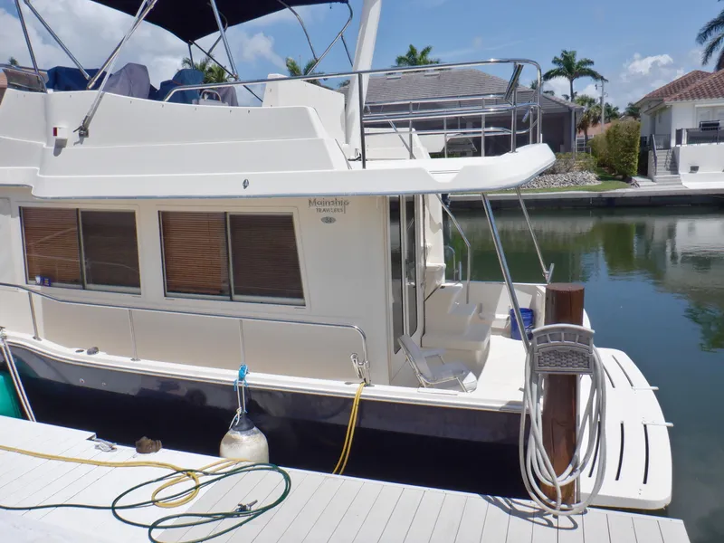Slide: The Image of 2006 Mainship 34 Trawler docked by a canal, featuring a spacious deck and modern design. - 15