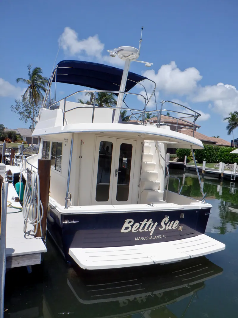 Slide: The Image of 2006 Mainship 34 Trawler docked, featuring "Betty Sue" name, blue canopy, and tropical backdrop. - 17