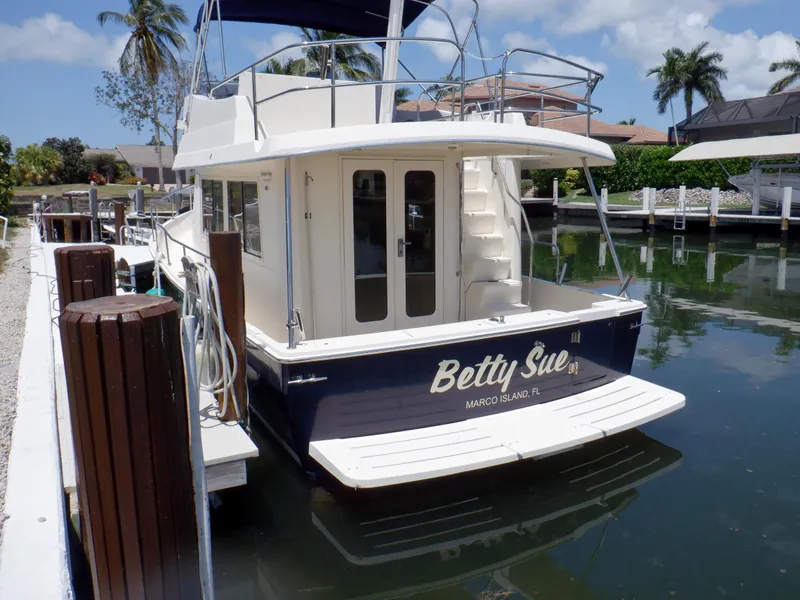 Slide: The Image of 2006 Mainship 34 Trawler docked, rear view, with "Betty Sue" name, palm trees in background. - 18