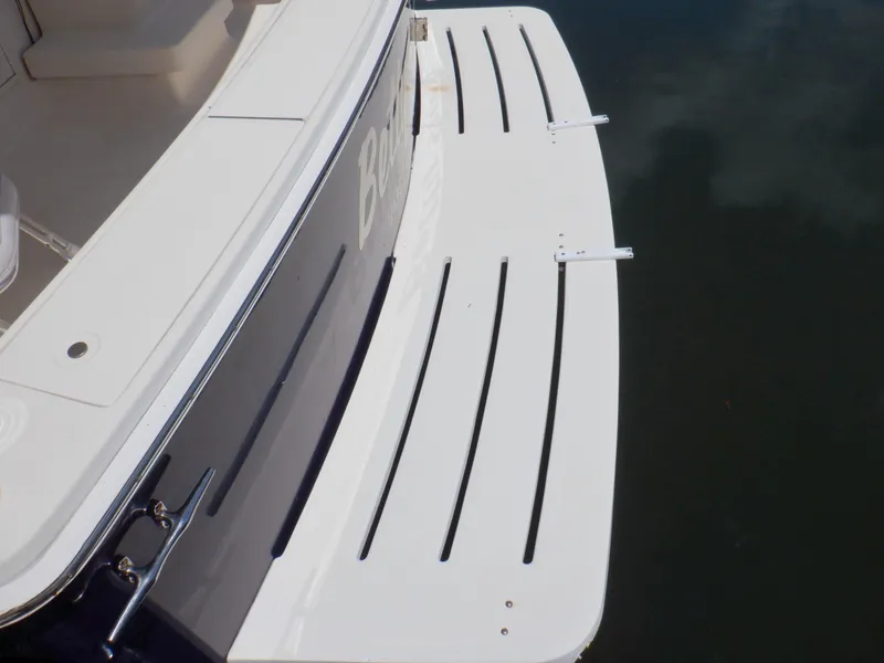 Slide: The Image of 2006 Mainship 34 Trawler swim platform, white with black slats, docked on calm water. - 19
