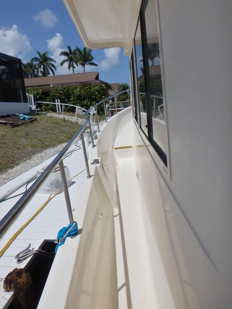 Slide: The Image of 2006 Mainship 34 Trawler side deck view with railing, under clear blue sky. - 20