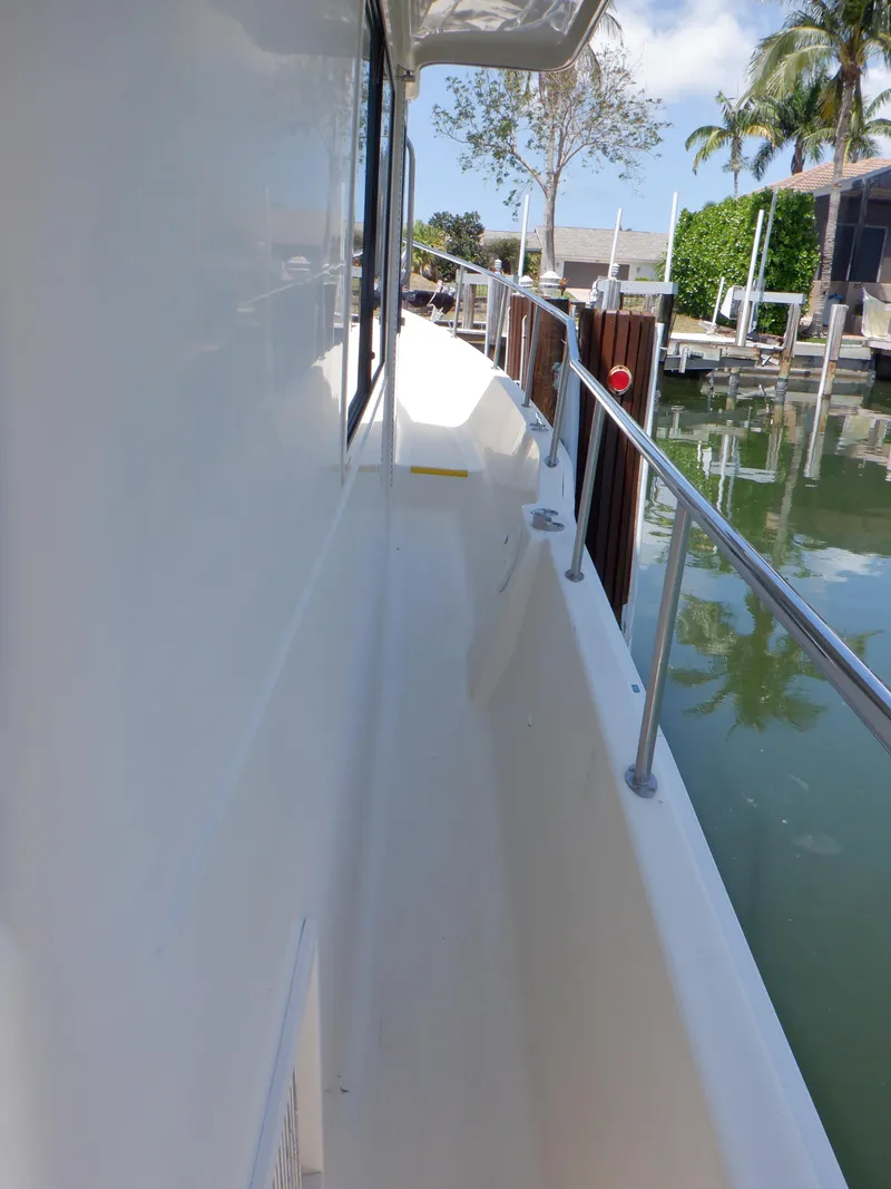 Slide: The Image of 2006 Mainship 34 Trawler side deck with railing, docked near water. - 24