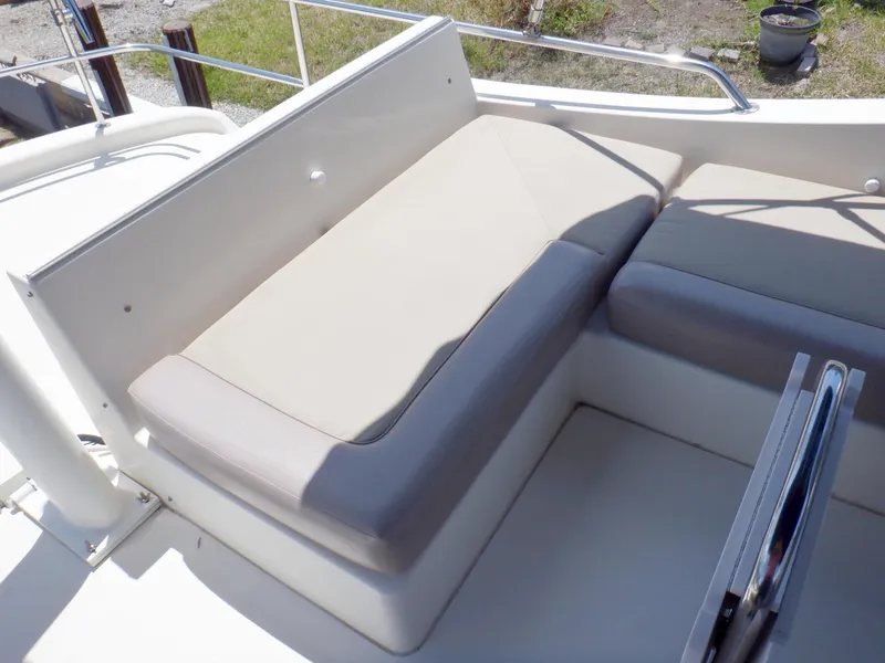 Slide: The Image of 2006 Mainship 34 Trawler seating area with beige cushions and stainless steel railing. - 26