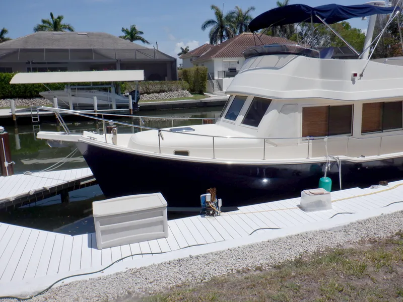 Slide: The Image of 2006 Mainship 34 Trawler docked at a marina with palm trees in the background. - 3