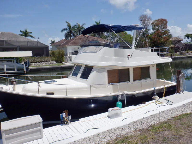 Slide: The Image of 2006 Mainship 34 Trawler docked by a canal, featuring a sleek design and spacious deck. - 4