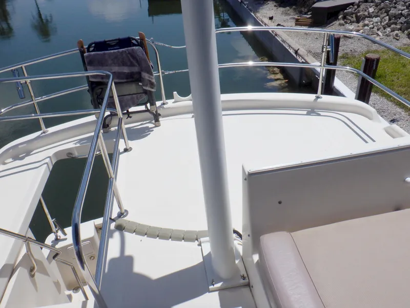 Slide: The Image of 2006 Mainship 34 Trawler deck with railing and seating, docked by calm water. - 44