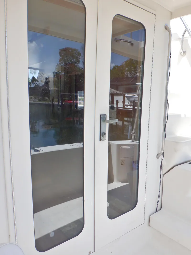 Slide: The Image of 2006 Mainship 34 Trawler with glass doors, docked by a serene waterfront. - 46