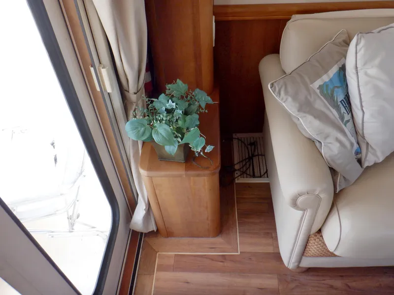 Slide: The Image of Interior of 2006 Mainship 34 Trawler with sofa, plant, and wooden flooring. - 48