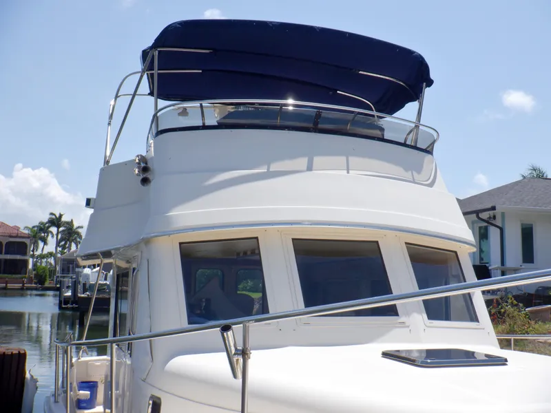 Slide: The Image of 2006 Mainship 34 Trawler with blue canopy docked in a sunny marina. - 5
