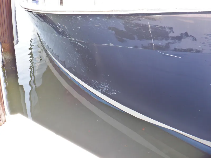 Slide: The Image of 2006 Mainship 34 Trawler hull with visible scratches, docked in calm water. - 6