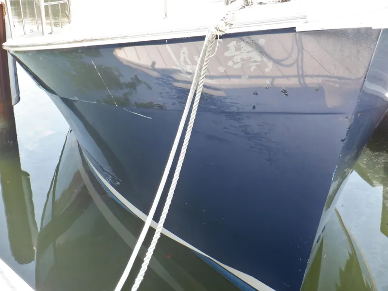 Slide: The Image of 2006 Mainship 34 Trawler with dark blue hull, docked and secured with ropes. - 7