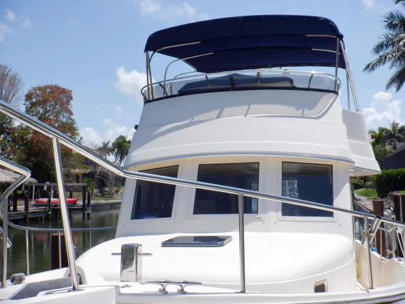 Slide: The Image of 2006 Mainship 34 Trawler with blue canopy, docked near palm trees. - 9