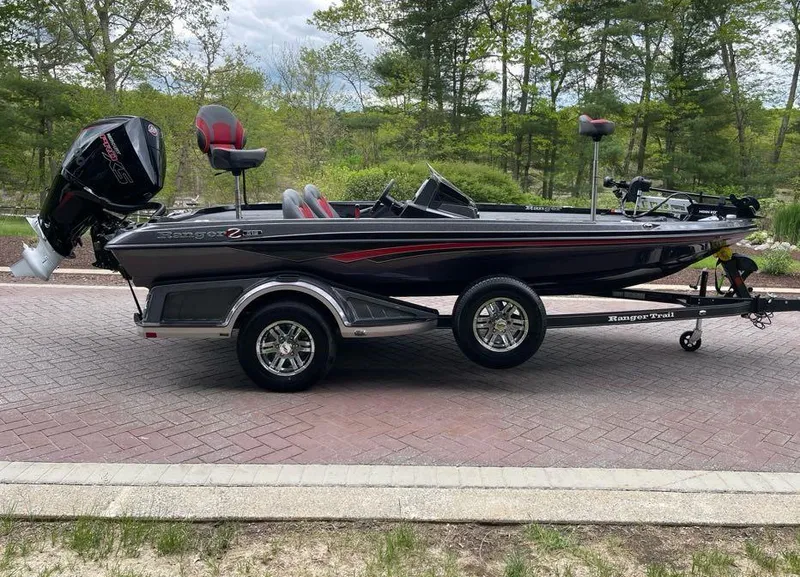 Slide: The Image of 2025 Ranger Z518 boat on trailer, parked on brick road, surrounded by trees. - 1