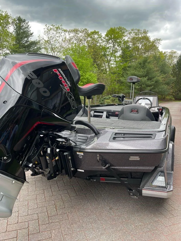 Slide: The Image of 2025 Ranger Z518 boat with powerful outboard motor, parked on paved surface, surrounded by trees. - 6