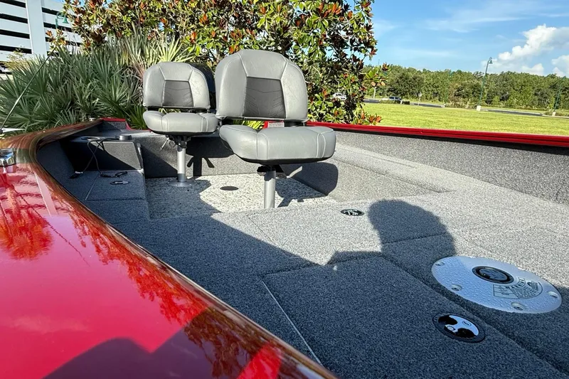 Slide: The Image of 2025 Tracker Super Guide V-16 T boat interior with two gray seats and red trim. - 2