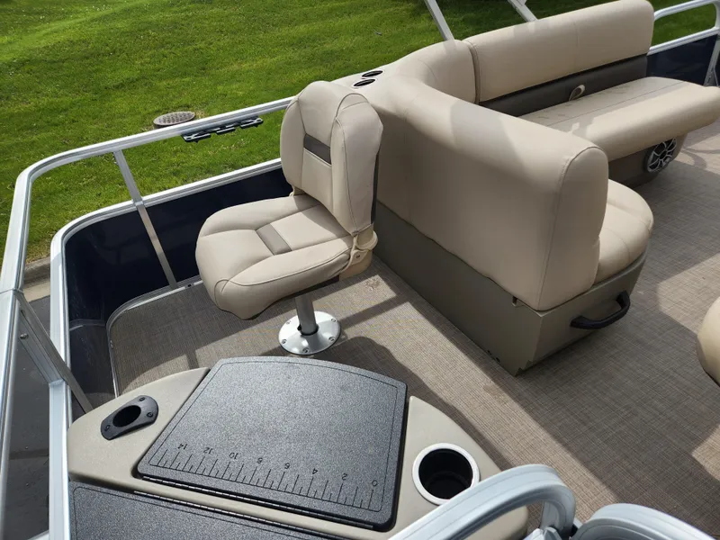 Slide: The Image of 2025 Sun Tracker Bass Buggy 18 DLX pontoon boat interior with beige seating and fishing station. - 4