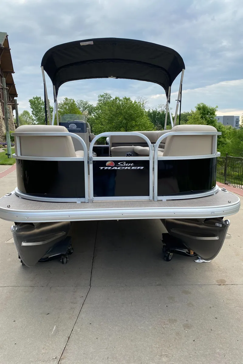 Slide: The Image of 2025 Sun Tracker Party Barge 16 DLX pontoon boat with canopy, docked outdoors. - 2