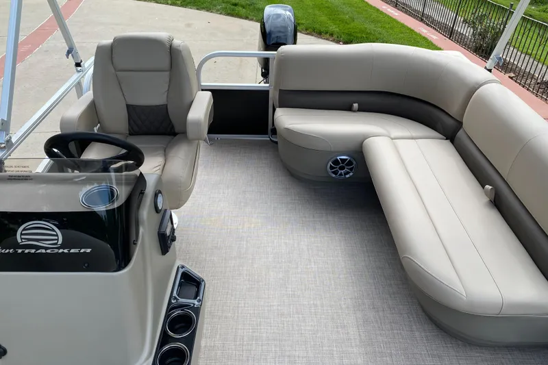 Slide: The Image of 2025 Sun Tracker Party Barge 16 DLX interior with beige seating and steering console. - 4