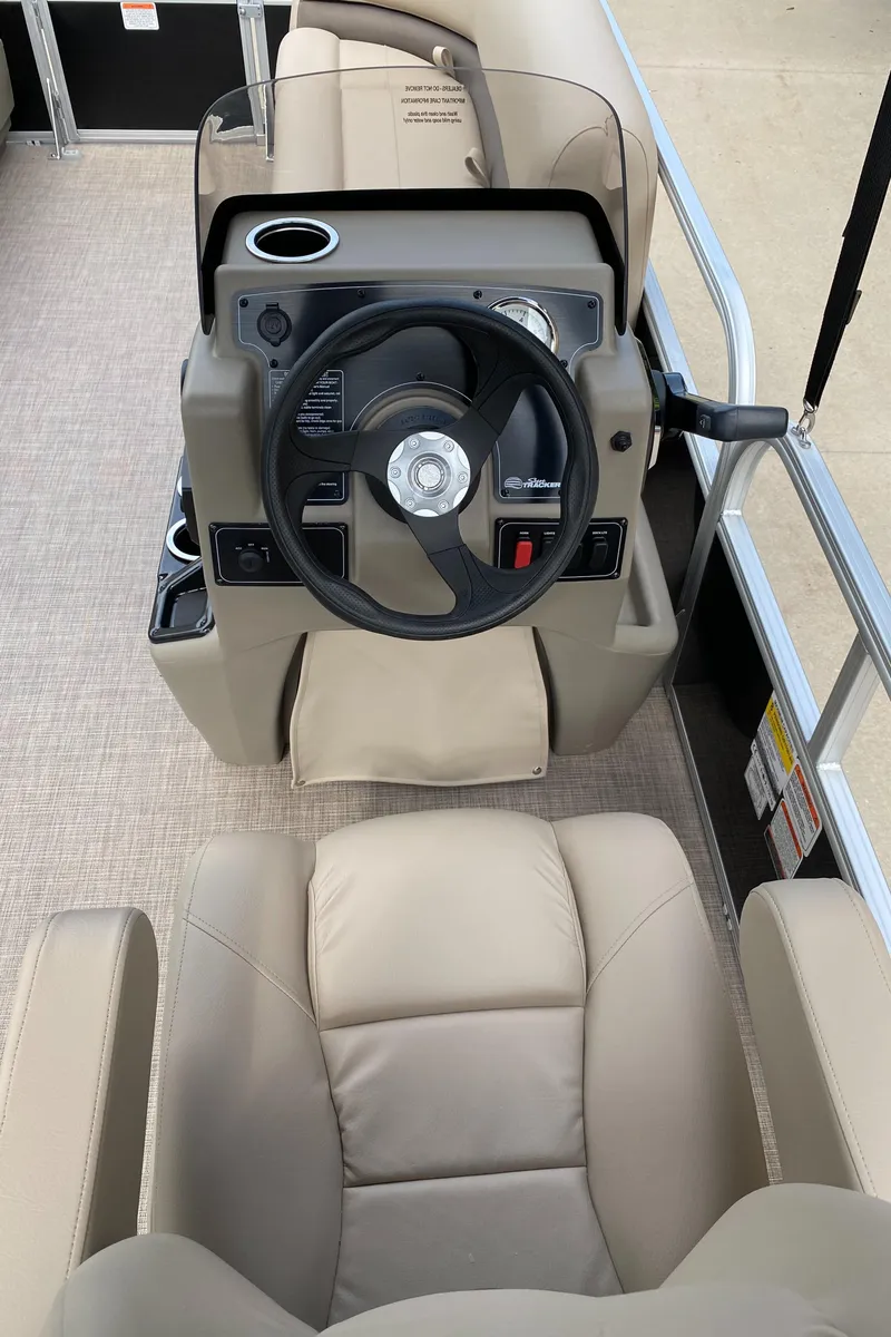 Slide: The Image of 2025 Sun Tracker Party Barge 16 DLX helm with beige seating and steering wheel. - 5