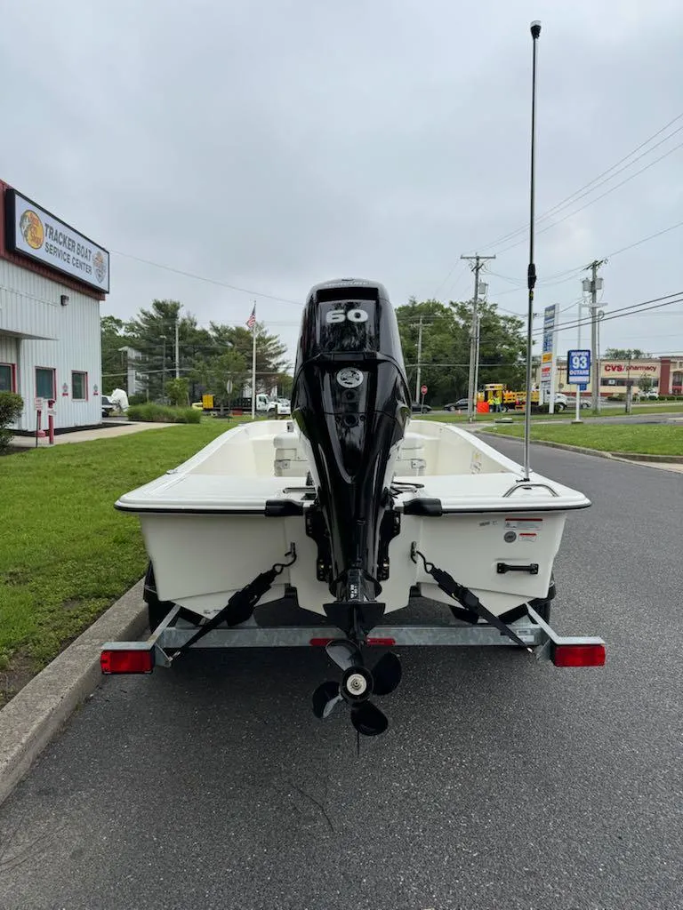Slide: The Image of 2025 Mako Pro Skiff 15 CC boat on trailer, rear view, parked near a building. - 3