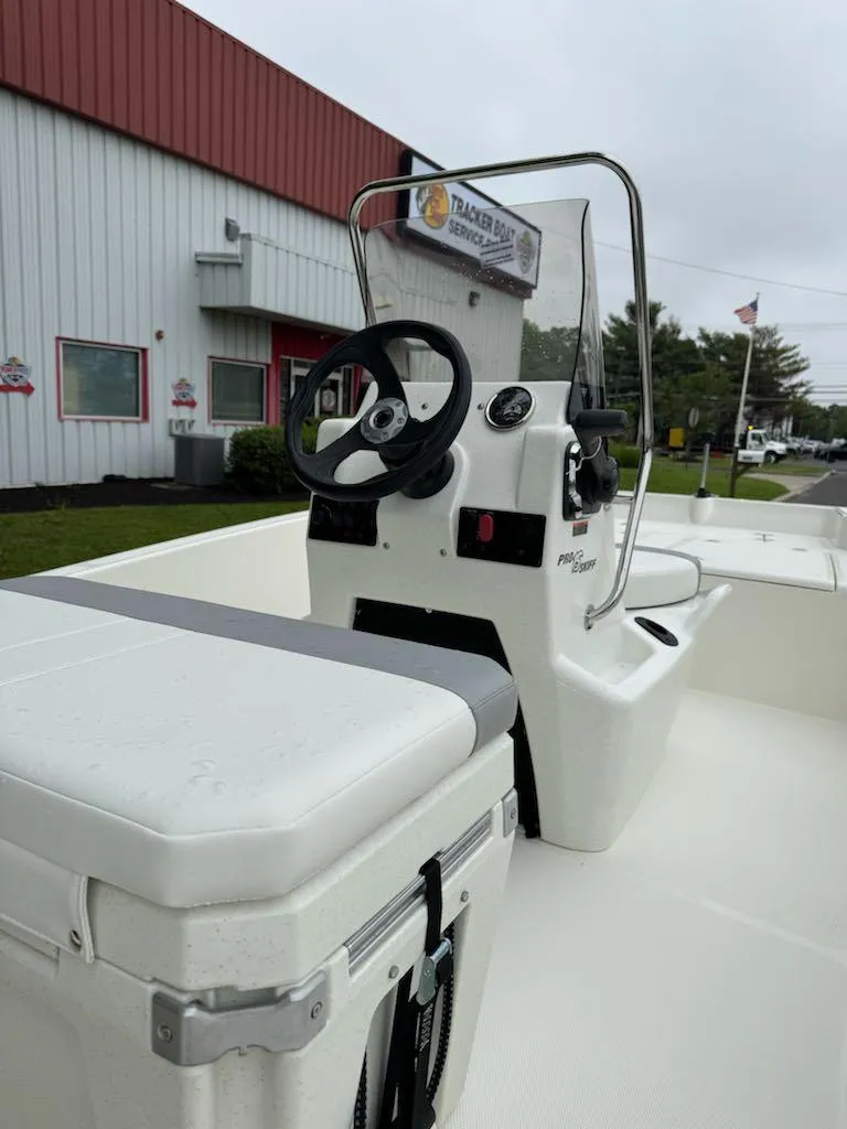 Slide: The Image of 2025 Mako Pro Skiff 15 CC boat, white interior, steering console, outdoor dealership setting. - 7