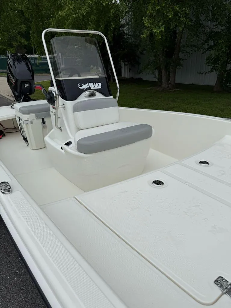 Slide: The Image of 2025 Mako Pro Skiff 15 CC boat with center console and seating, parked outdoors. - 8