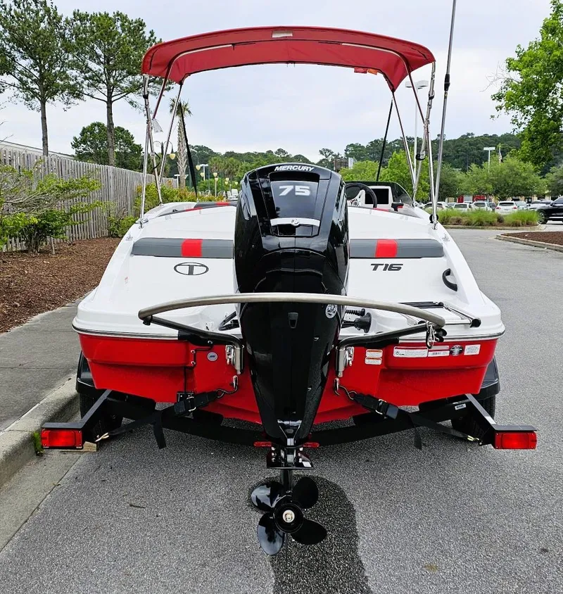 Slide: The Image of 2025 Tahoe T16 boat with Mercury 75 engine, red and white design, parked on a road. - 3