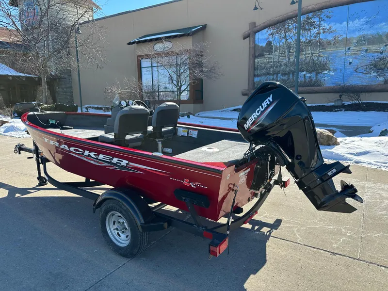 Slide: The Image of 2025 Tracker Super Guide V-16 SC boat with Mercury engine, parked outdoors. - 2