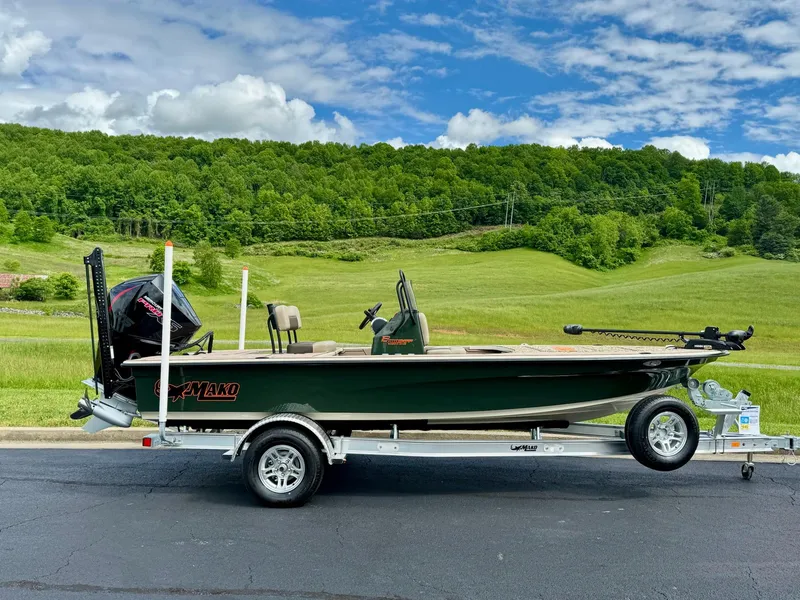 The Image of 2025 Mako 18 Pro Skiff Backwater Edition on trailer, set against lush green landscape. - 0