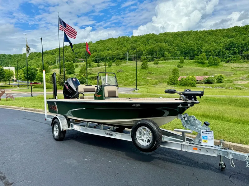 Slide: The Image of 2025 Mako 18 Pro Skiff Backwater Edition on trailer, parked outdoors with scenic background. - 1