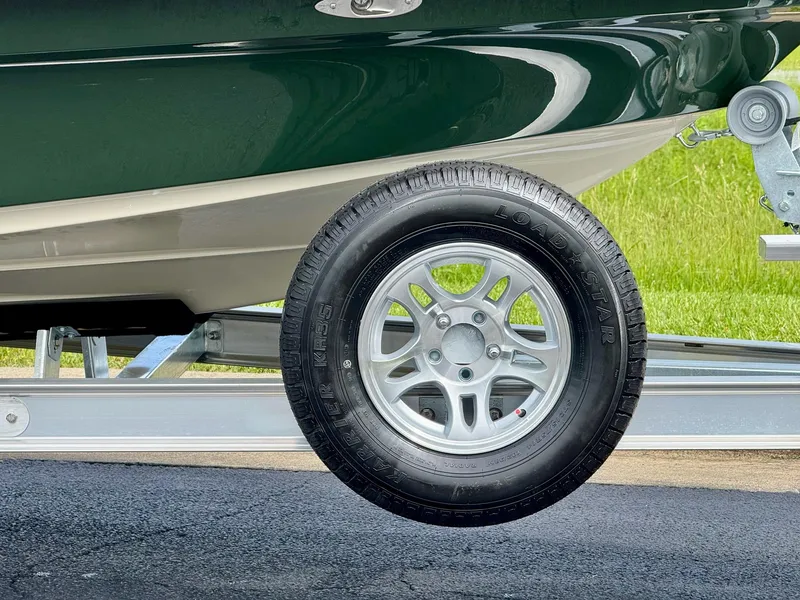 Slide: The Image of 2025 Mako 18 Pro Skiff Backwater Edition trailer wheel on pavement. - 3