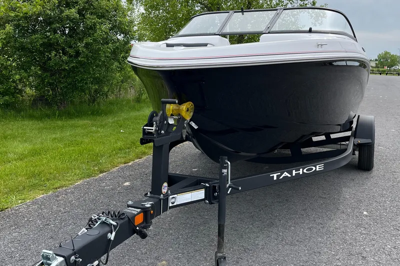 Slide: The Image of 2025 Tahoe 185 S boat on trailer, parked on a paved road near greenery. - 7