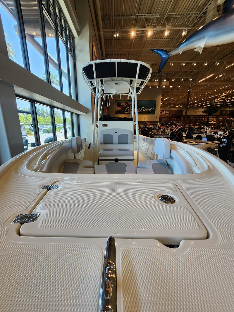Slide: The Image of 2025 Mako 214 CC boat displayed indoors, showcasing spacious deck and seating. - 2