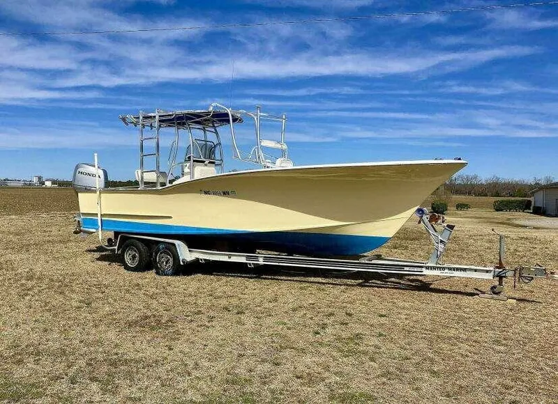 Slide: The Image of Custom 24 OPEN 1995 boat on trailer, parked on grassy field under blue sky. - 0