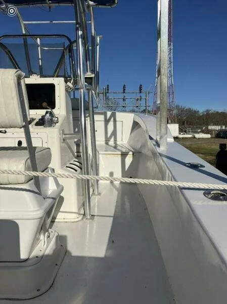 Slide: The Image of Custom 24 OPEN 1995 boat deck with seating and railing under clear blue sky. - 13
