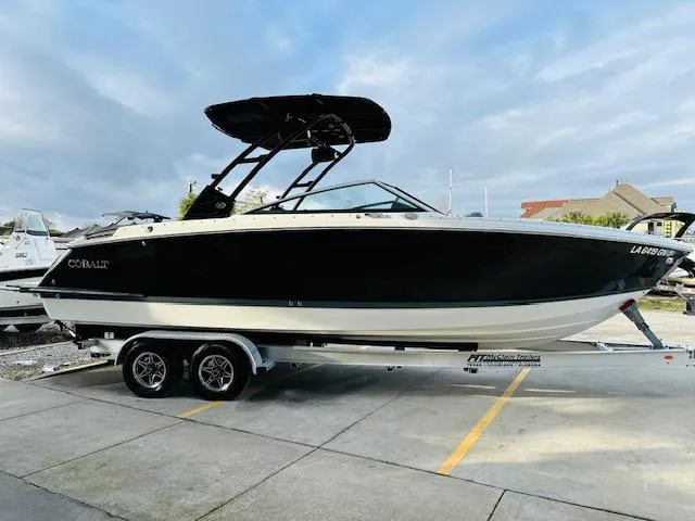 The Image of 2022 Cobalt R8 boat on trailer, black hull, sleek design, parked outdoors. - 1