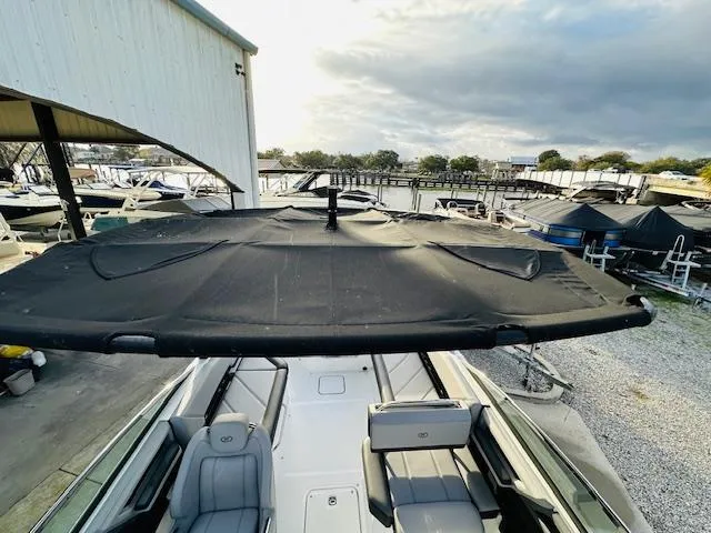 Slide: The Image of 2022 Cobalt R8 boat with black canopy, docked near a marina under cloudy skies. - 24