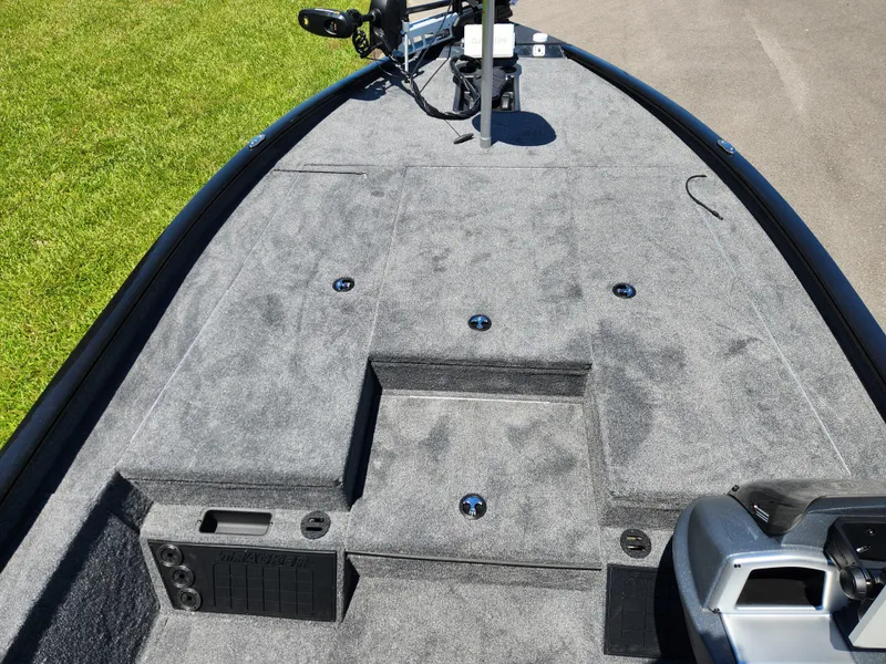 Slide: The Image of 2025 Tracker Savage 215 boat deck with gray carpet and fishing equipment. - 12