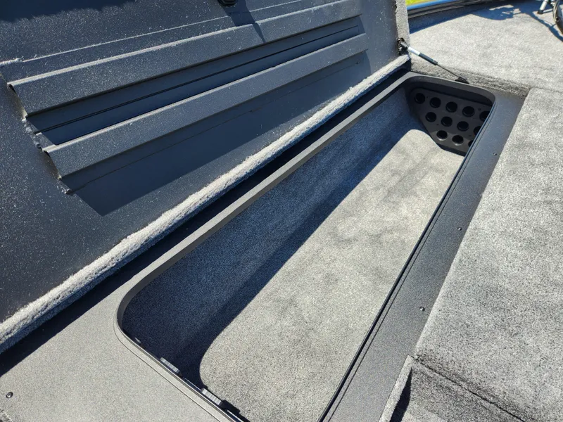 Slide: The Image of 2025 Tracker Savage 215 boat storage compartment with carpeted interior and organized layout. - 13