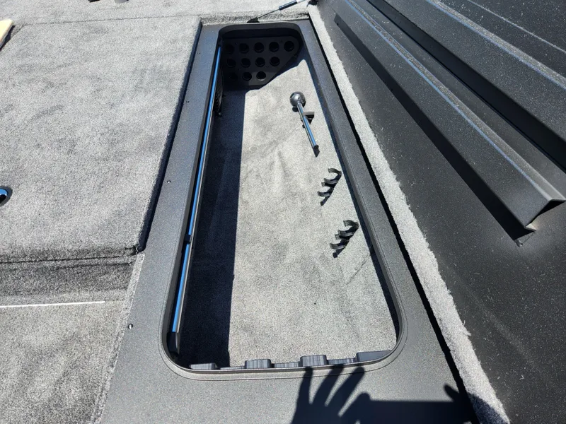 Slide: The Image of 2025 Tracker Savage 215 boat storage compartment with carpeted interior and rod holders. - 15