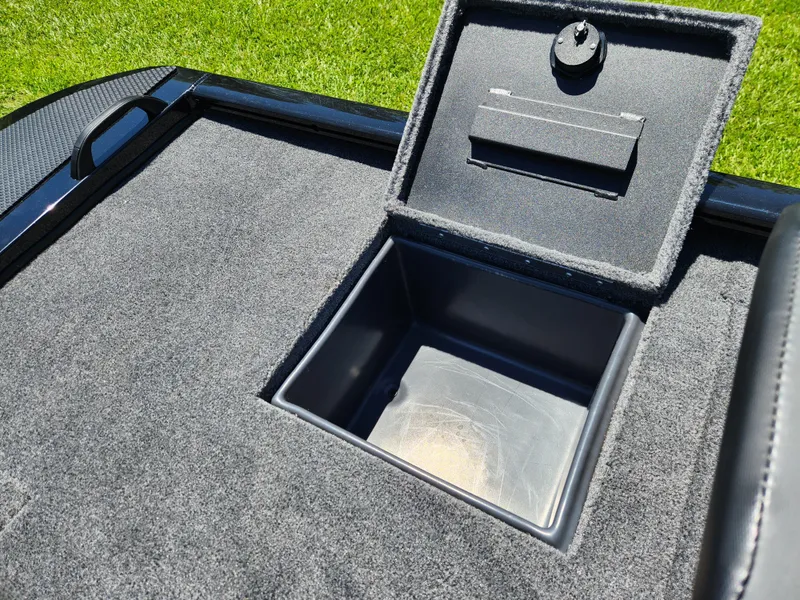 Slide: The Image of Open storage compartment on 2025 Tracker Savage 215 boat, featuring carpeted interior. - 18