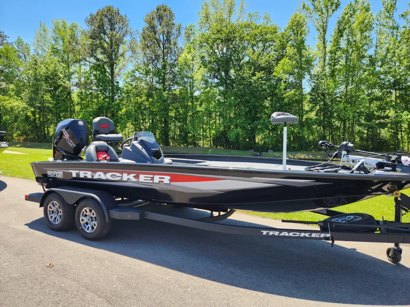 Slide: The Image of 2025 Tracker Savage 215 boat on trailer, parked on road with trees in background. - 3