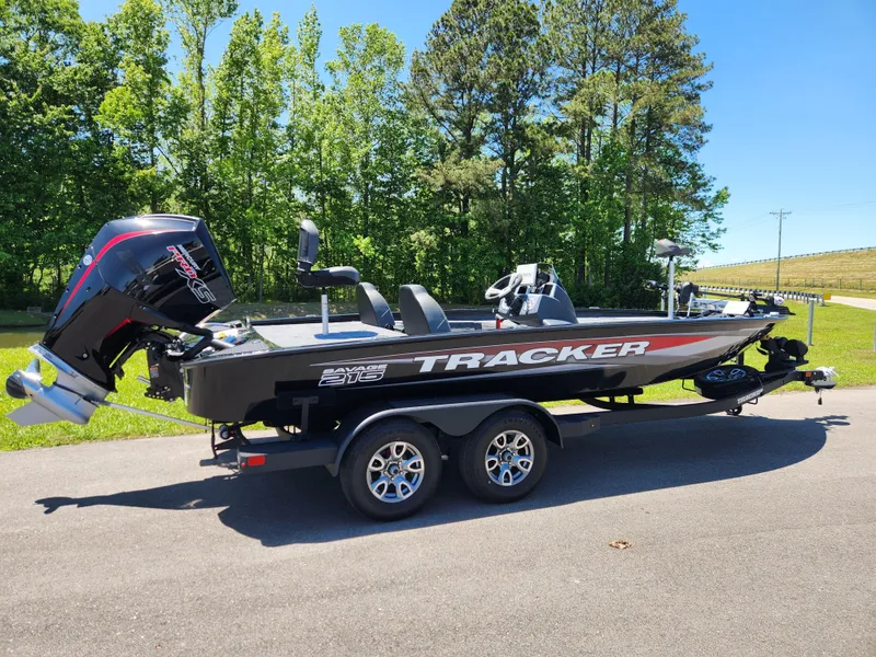 Slide: The Image of 2025 Tracker Savage 215 boat on trailer, parked on road with trees in background. - 4